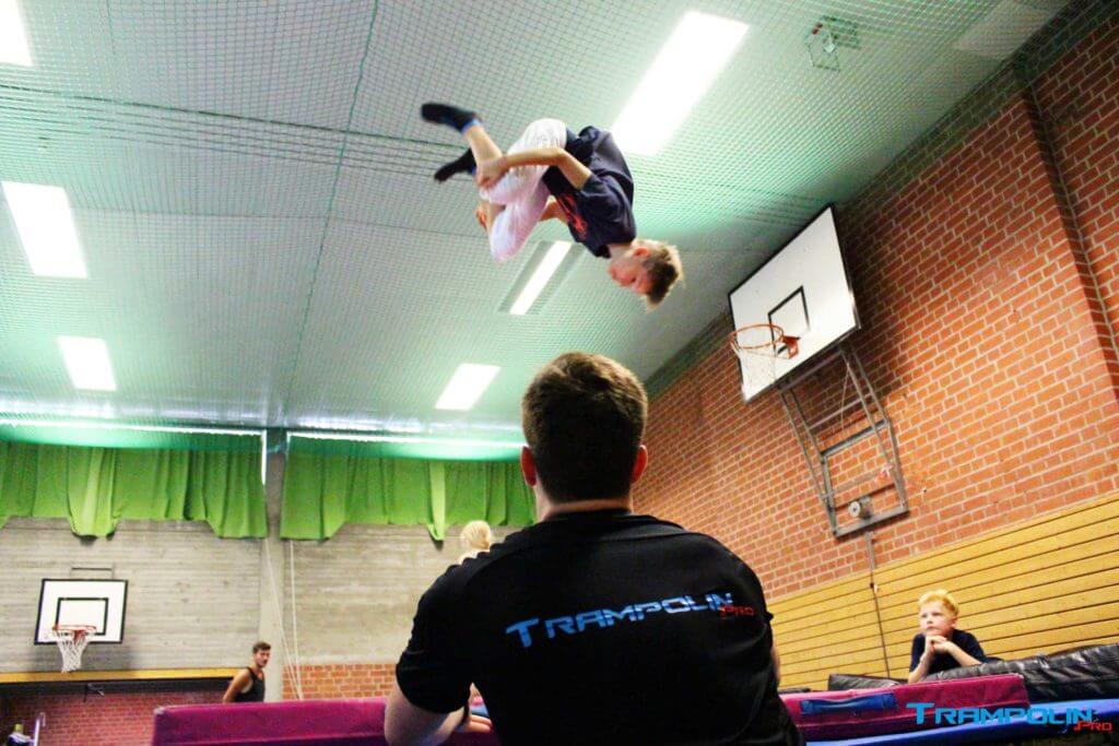 Trampolin springen mit Unterstützung durch einen Trainer